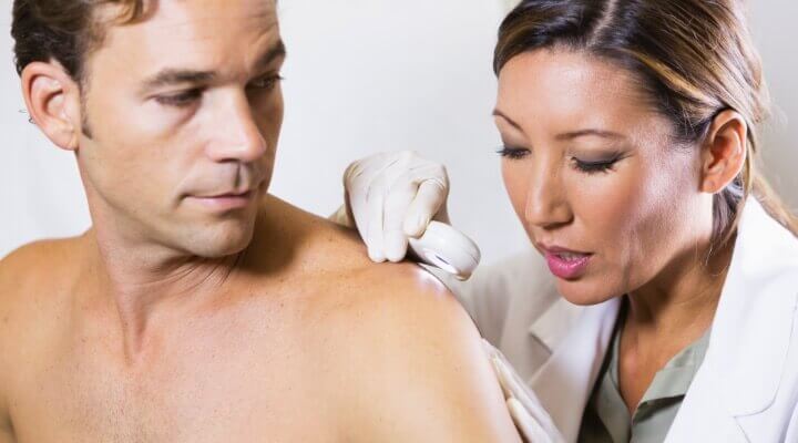 Dermatologist examining skin on a man's shoulder